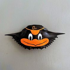 an orange and black bird with big eyes on it's face is hanging from the wall