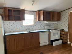 an empty kitchen with wooden cabinets and white appliances