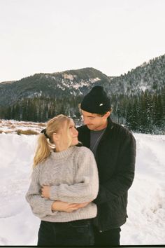 a man and woman are standing in the snow