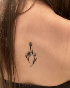 the back of a woman's neck with a flower tattoo on her left shoulder