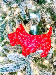 a red ornament hanging from the side of a christmas tree