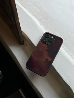 a cell phone sitting on top of a white counter next to a window sill