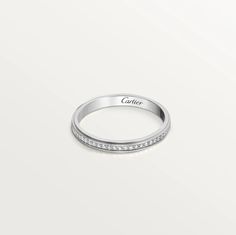 a white gold wedding band with channeled diamonds set in the center, on a plain surface