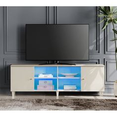 an entertainment center with a large television on it's stand in front of a gray wall