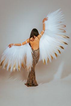 a woman dressed in gold and white with wings on her back, posing for the camera