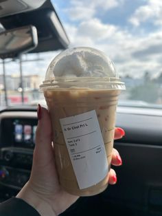 a woman holding up a cup of iced coffee in her hand with a ticket attached to it