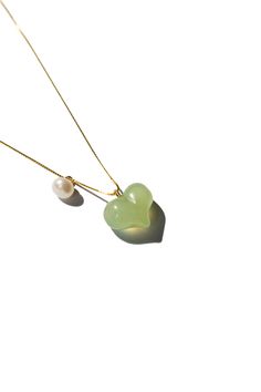 The Puffed Heart Necklace features a green jade heart pendant, puffed to perfection, complemented by a delicate pearl. The unique puffed design of the jade heart adds a playful touch, making it an irresistibly cute accessory. Avoid knocking against hard surfaces. Jade pieces are brittle and will break when hit with hard objects. Make sure that you take off your jewelry before you go swimming in a pool or hot tub. If you’re handling dirt and soil, quartz dust in soil is abrasive to the stone. Avo Fine Jewelry Green Heart Jewelry, Green Heart Pendant Necklace For Mother's Day, Green Heart-shaped Fine Jewelry, Green Heart Shaped Fine Jewelry, Green Heart Charm Jewelry For Anniversary, Elegant Green Necklace For Keepsake, Green Heart Charm Jewelry For May Birthstone, Green Heart Charm Jewelry For Wedding, Green Necklace With Heart Charm For Anniversary