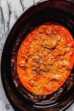 an overhead view of a slow cooker filled with tomato sauce and ground meats