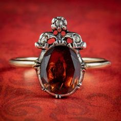 An exquisite Georgian inspired ring boasting a deep red flat cut Garnet weighing approx. 2.5ct framed in a closed back Silver gallery with 18ct Gold band. A Fleur de Lis can also be seen growing out from the top and is dotted with three twinkling rose cut Diamonds. It's a fabulous tribute to Georgian design and looks gorgeous laid flat against the finger. We recommend you insure for £1,750. We can provide a written Valuation on completion of the sale. WEIGHT: 2.6 grams MEASURES: Size J ½ (UK), 5 Formal Garnet Gemstone Diamond Ring, Oval Red Rose Cut Diamond Jewelry, Formal Red Diamond Ring With Rose Cut Diamonds, Victorian Style Red Oval Diamond Ring, Victorian Oval Red Diamond Ring, Antique Red Gemstone Diamond Ring, Antique Red Diamond Ring With Gemstone, Classic Red Pear-shaped Rings, Red Oval Rings With Rose Cut Diamonds