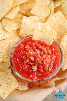 a glass bowl filled with salsa surrounded by tortilla chips