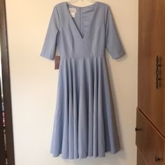 a blue dress hanging on a wall next to a wooden door with a white hanger