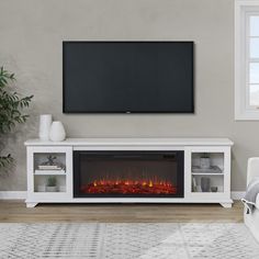 a white entertainment center with a fireplace and tv on it's stand in front of a window