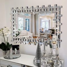 a living room filled with furniture and a large mirror over the top of a table