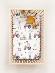 a baby's crib with a toy truck and farm animals on the sheet