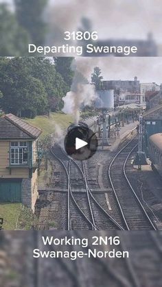 a train traveling down tracks next to a small town with buildings and trees in the background