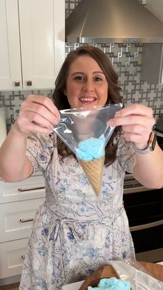 a woman holding an ice cream cone with blue icing in her hands and smiling