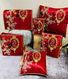 four red and gold embroidered pillows, one with a monogrammed name on it