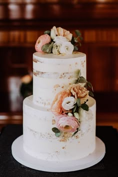 a three tiered wedding cake with flowers on top