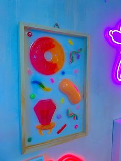 an art work is displayed on the wall next to a neon sign and other items