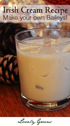 a glass filled with liquid sitting on top of a wooden table next to pine cones