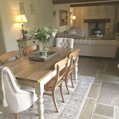 a dining room table and chairs in front of a couch with pillows on the back