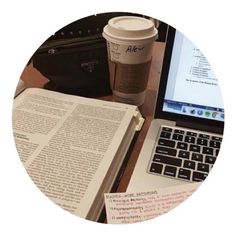 a laptop computer sitting on top of a desk next to a cup of coffee and an open book