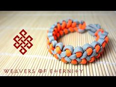 an orange and gray bracelet with two silver beads on it, sitting on top of a bamboo mat