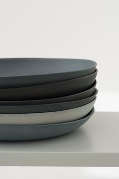 four black and silver plates stacked on top of each other in front of a white wall