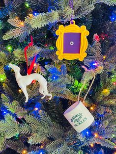 a christmas tree with ornaments on it and a cup hanging from the branch in front