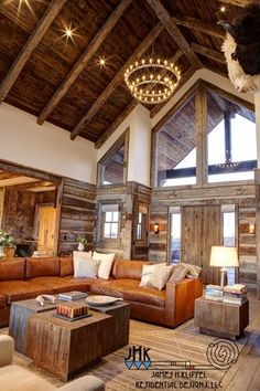 a living room filled with lots of furniture and wooden beams on the ceiling is lit by lights