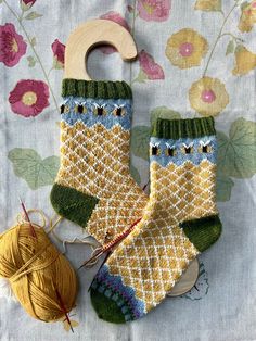 two knitted socks sitting on top of a table next to yarn