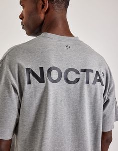 Nike and Drake are back with a new NOCTA collection. This short-sleeve T-shirt features a subtle center-chest Swoosh on the front, while the back boasts bold NOCTA graphics. Swoosh on the front NOCTA graphic on the back Short sleeves Ribbed crewneck collar Cotton material Relaxed fit Grey Tee, Boy Shoes, Spring Shoes, Jordan Retro, Armani Exchange, Nike Jordan, Tight Leggings, Sport Shorts, Outerwear Jackets