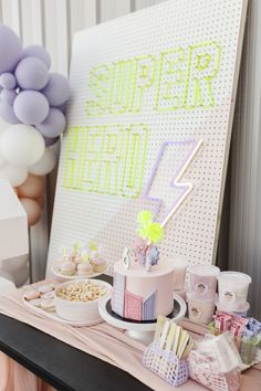 a table topped with cakes and desserts next to balloons