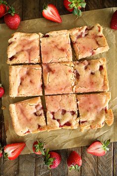 strawberry shortbreads cut into squares and placed on wax paper with strawberries around them