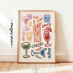 a framed art print with various drinks and cocktails on it in front of a white wall