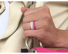 a close up of a person's hand holding a pink and white ring on their finger