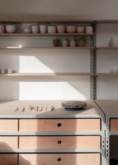 a shelf with bowls and cups on it next to a cabinet filled with other items