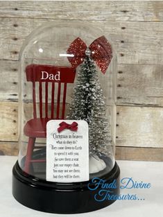 a snow globe with a christmas tree under it and a card attached to the base