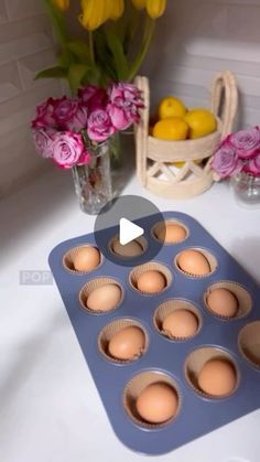 a muffin pan filled with eggs sitting on top of a counter next to flowers