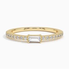 a yellow gold ring with a baguette cut diamond set in the center and side stones