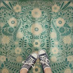 someone's feet are standing on a floral wallpaper