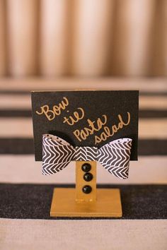 a black and white sign with a bow tie on it's head sitting on top of a table