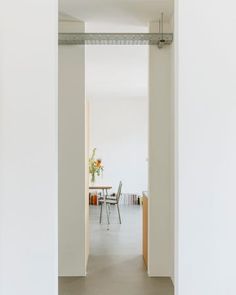 an open door leading to a dining room with chairs and table in the background on a white wall