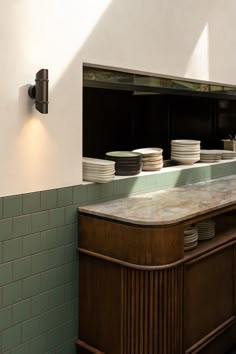 an empty counter in a restaurant with plates stacked on it's back and the lights on