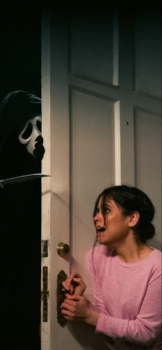 a woman is opening the door with her mouth wide open and a ghost behind her