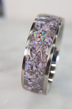 a close up of a ring with purple and silver glitters on the inside of it