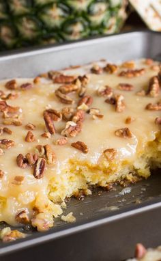 a close up of a cake in a pan with pecans on top and one slice missing