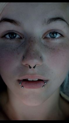 a woman with piercings on her nose looking at the camera