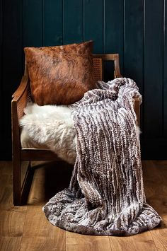 a chair with a blanket on top of it next to a pillow and some pillows