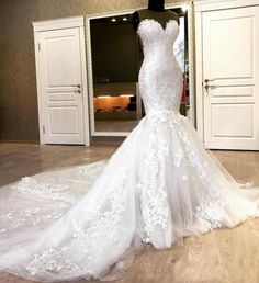 a white wedding dress on display in front of a mirror with an open door behind it